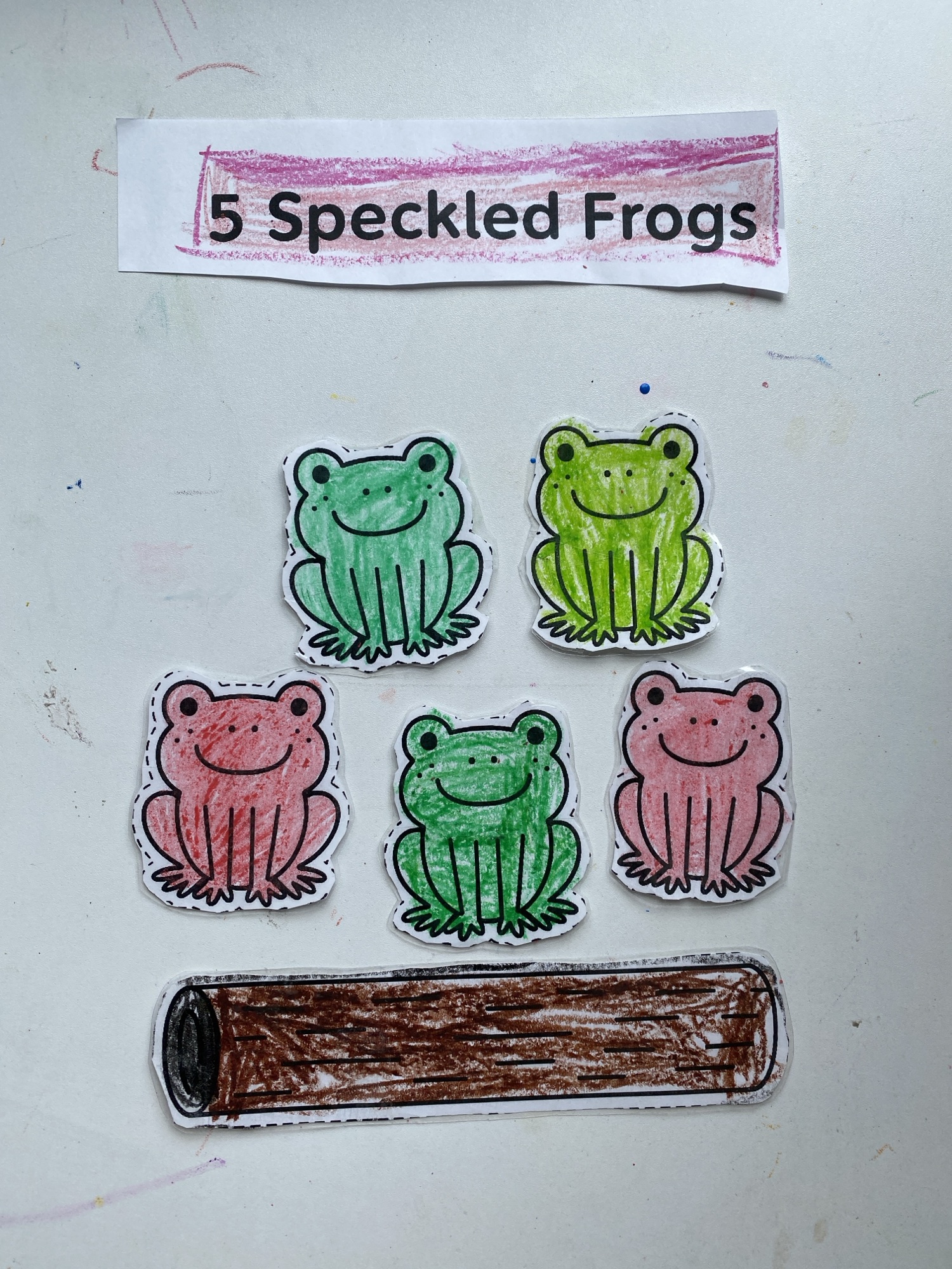 5 speckled frogs taped on the wall