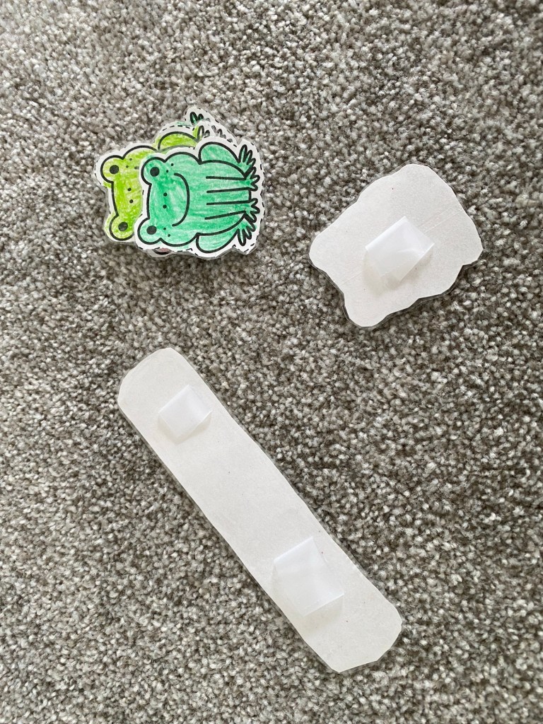 putting tape on the back of the frogs and log