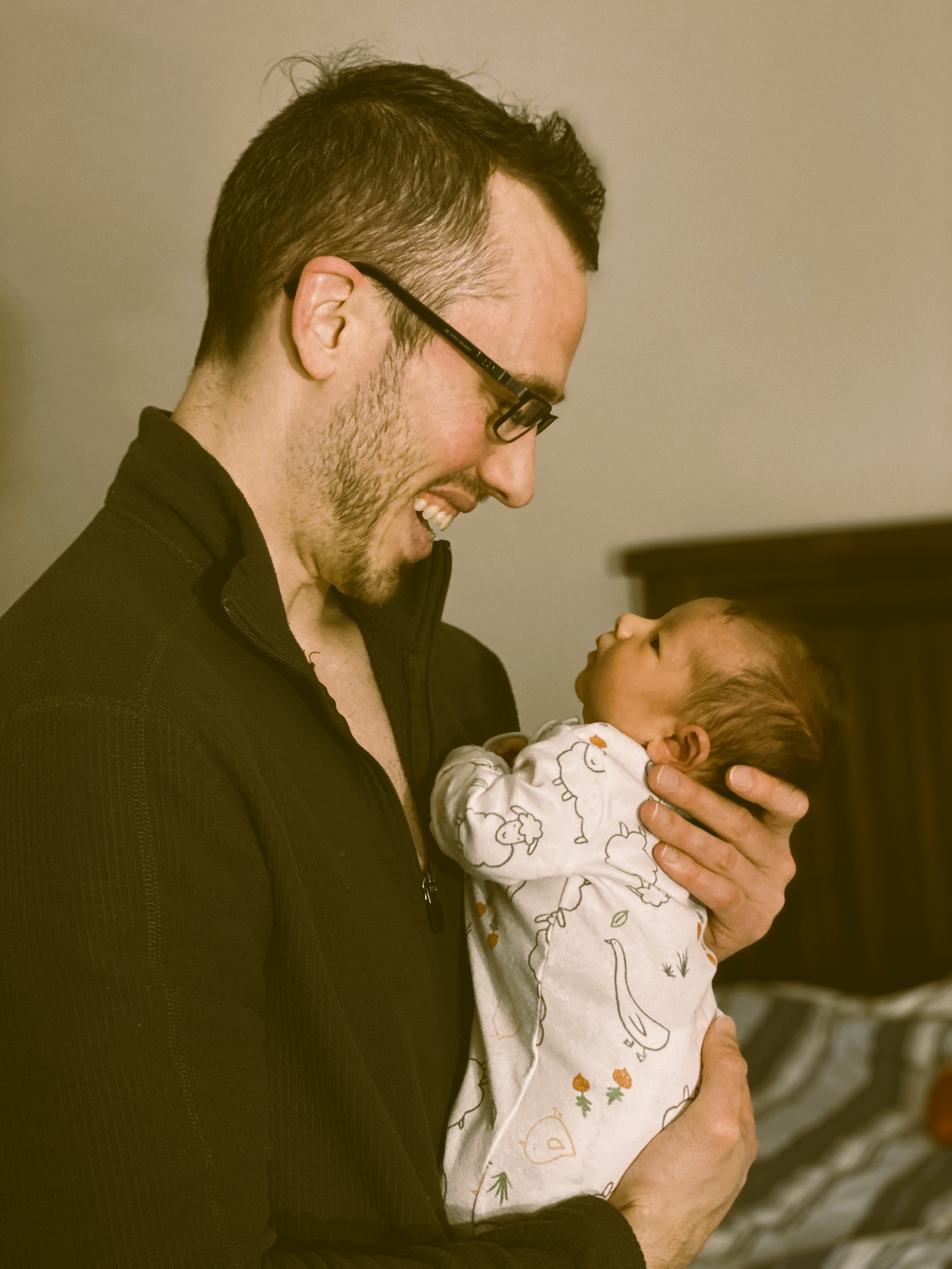 father smiles at newborn baby with love